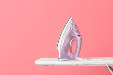 Renk arkaplanında elektrikli ütü ve tahta