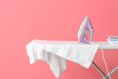 Arkaplanda elektrikli ütü ve temiz giysiler bulunan tahta