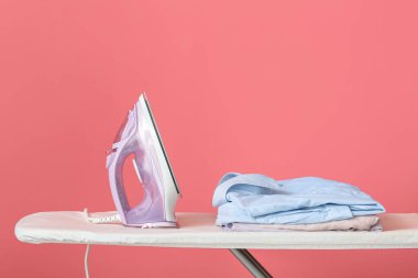 Arkaplanda elektrikli ütü ve temiz giysiler bulunan tahta