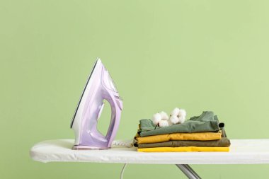 Arkaplanda elektrikli ütü ve temiz giysiler bulunan tahta