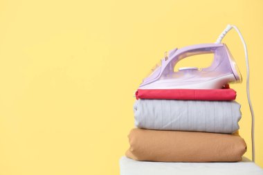 Arkaplanda elektrikli ütü ve temiz giysiler bulunan tahta