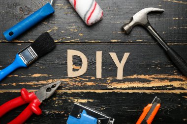 Aletlerden yapılmış çerçeve ve koyu ahşap arka planda kelime DIY