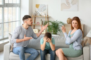 Üzgün küçük çocuk ve kavgacı ailesi evde.