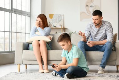Küçük çocuk cep telefonu kullanıyor ve üzgün ailesi evde.