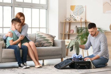 Eşyalarını toplayan bir adam ve evde küçük çocukla üzgün bir kadın.