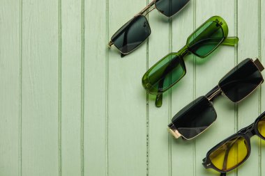 Renkli ahşap arka planda farklı modern güneş gözlükleri