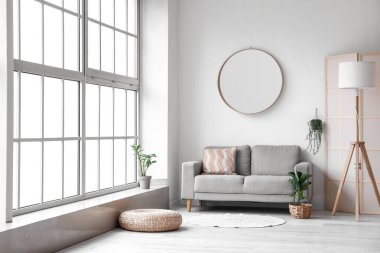 Rahat kanepesi, aynası ve lambası olan modern bir oda.