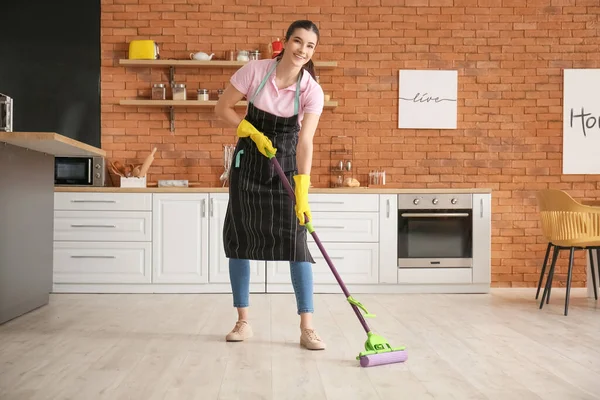 Mutfakta yerleri paspaslayan genç kadın.