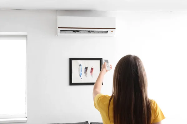 Jonge Vrouw Met Airconditioner Afstandsbediening Thuis — Stockfoto