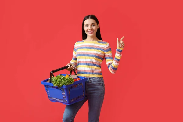 Mujer Joven Con Cesta Compra Apuntando Algo Fondo Color — Foto de Stock