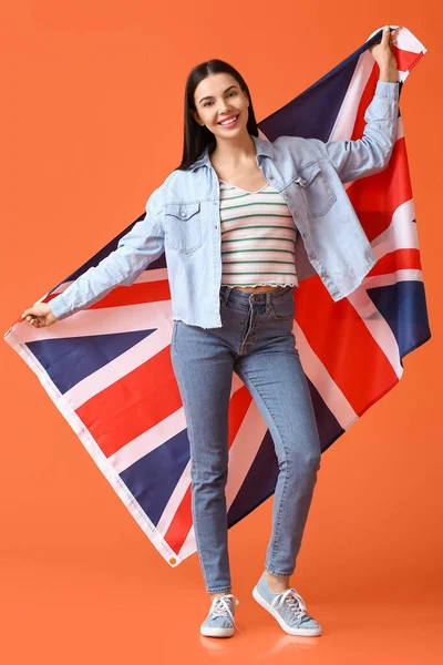 Beautiful young woman with the flag of Great Britain on color background