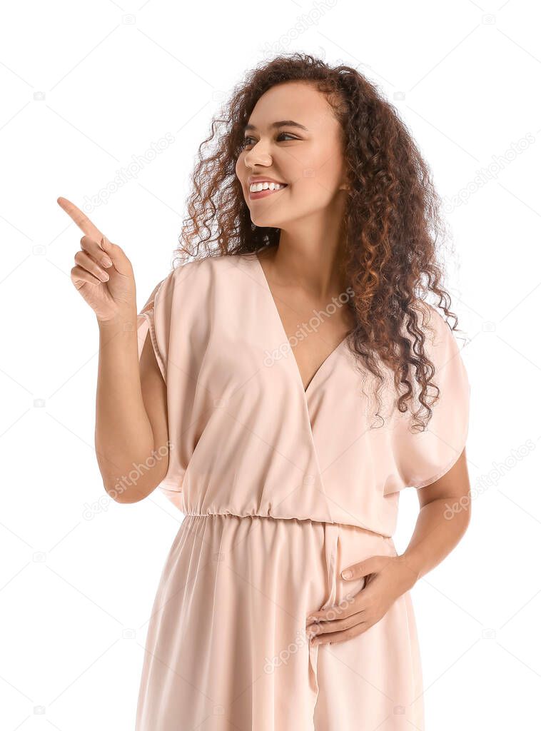 Pregnant African-American woman pointing at something on white background