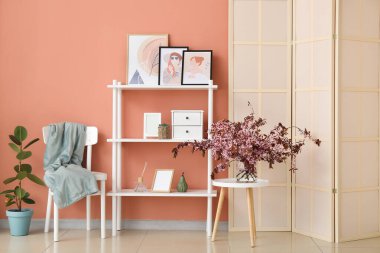 Oturma odasının içindeki masada çiçek açan dalları olan vazo.