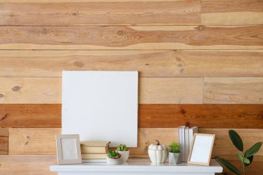 Ahşap duvarın yanında kitap ve çerçeveleri olan modern şömine rafı.