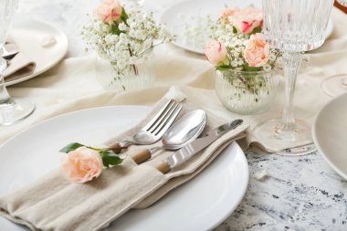 Açık arkaplanda çiçek dekoru olan güzel masa ayarları, yakın plan.