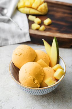 Bowl with tasty mango ice cream on light background
