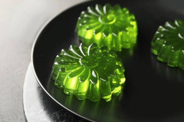 Plate with tasty kiwi jelly on dark background
