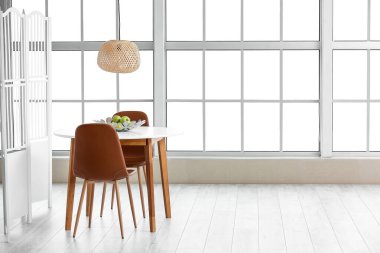 Dining table with apples near window in room
