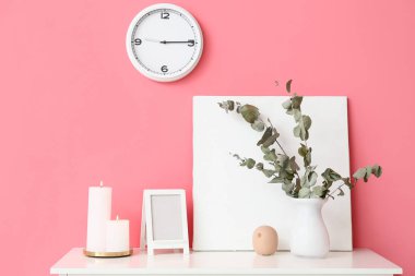 Burning candles with decor on table near color background