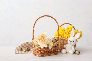 Beautiful Easter composition with narcissus flowers, quail eggs and toy on light background