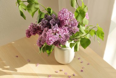 Masada güzel leylak çiçekleri olan vazo.