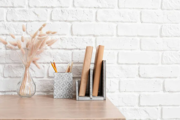 Table with books and organizers near brick wall