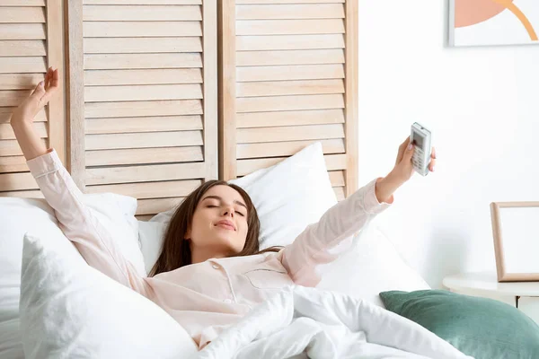 Young Woman Air Conditioner Remote Control Lying Bed — Stock Photo, Image