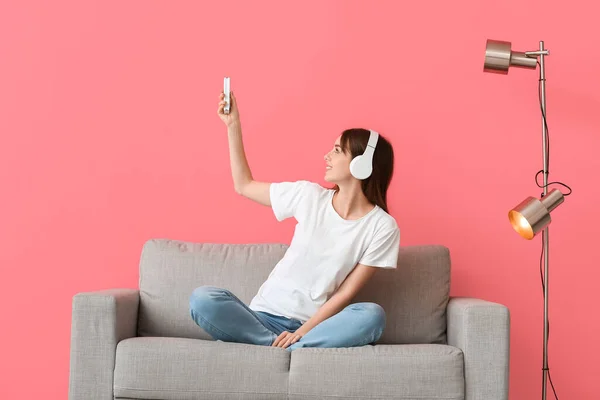 Young Woman Air Conditioner Remote Control Sitting Sofa Color Wall — Stockfoto