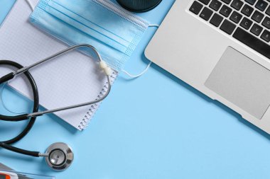 Composition with modern stethoscope and laptop on color background
