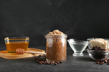 Kavanoz dolusu doğal vücut fırçası ve koyu arkaplanda malzemeler.