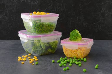 Esmer arka planda sebzeli plastik kaplar.
