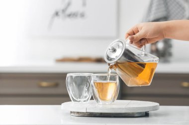 Kadın çaydanlıktan bardaklara sıcak çay dolduruyor.