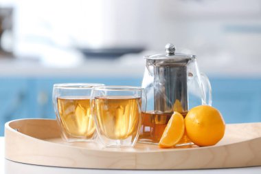 Çaydanlık, bardaklar sıcak çay ve portakallı mutfak tepsisi.