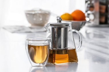 Çaydanlık ve bardak, mutfaktaki masada sıcak çay.