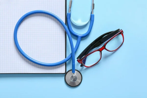 Composition Modern Stethoscope Notebook Eyeglasses Color Background Closeup — Zdjęcie stockowe