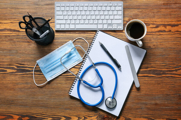 Composition with modern stethoscope and computer keyboard on wooden background