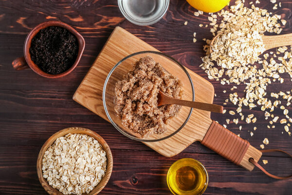 Bowl of natural body scrub and ingredients on wooden background