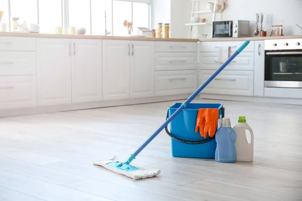 Set of cleaning supplies on floor in kitchen