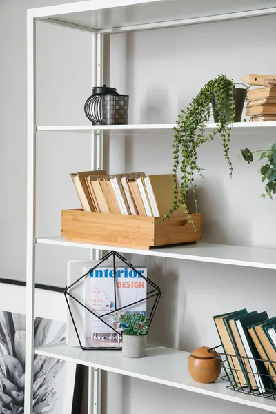 Modern book shelf with decor near light wall