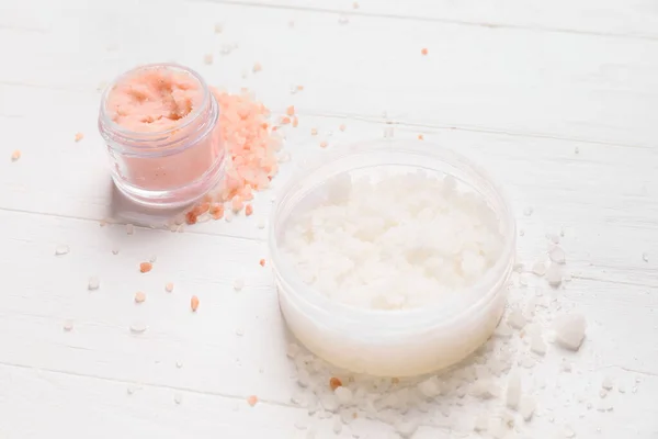 Jars of body scrub on light wooden background