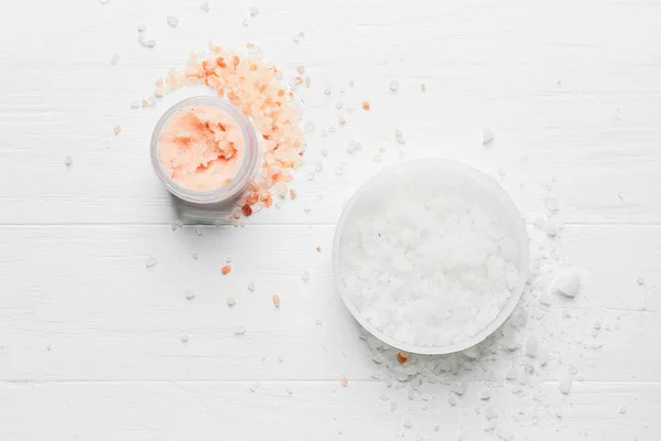 Jars of body scrub on light wooden background