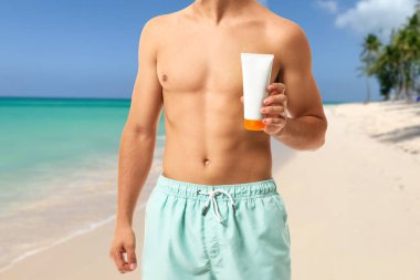 Young man with sun protection cream at sea resort