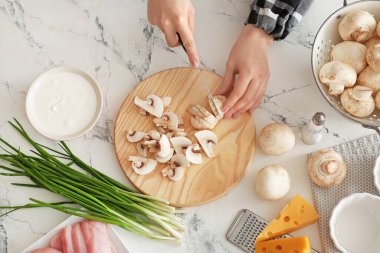 Woman cutting mushrooms on light background