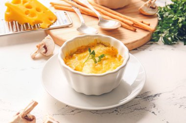 Ramekin with tasty julienne and ingredients on light background