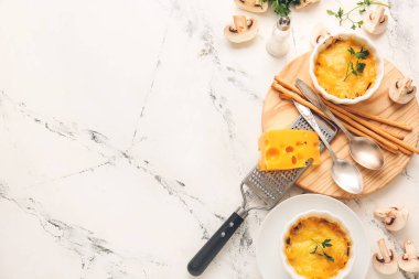 Ramekins with tasty julienne and ingredients on light background