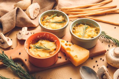 Ramekins with tasty julienne and ingredients on color background