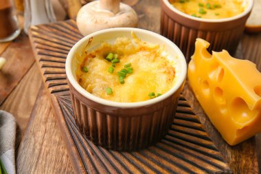 Ramekin with tasty julienne and ingredients on wooden background, closeup
