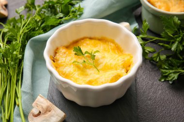 Ramekin with tasty julienne and ingredients on dark background, closeup