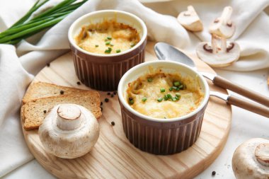 Ramekins with tasty julienne and ingredients on light background