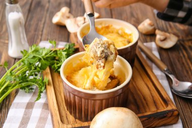 Woman holding spoon with tasty julienne on wooden background, closeup